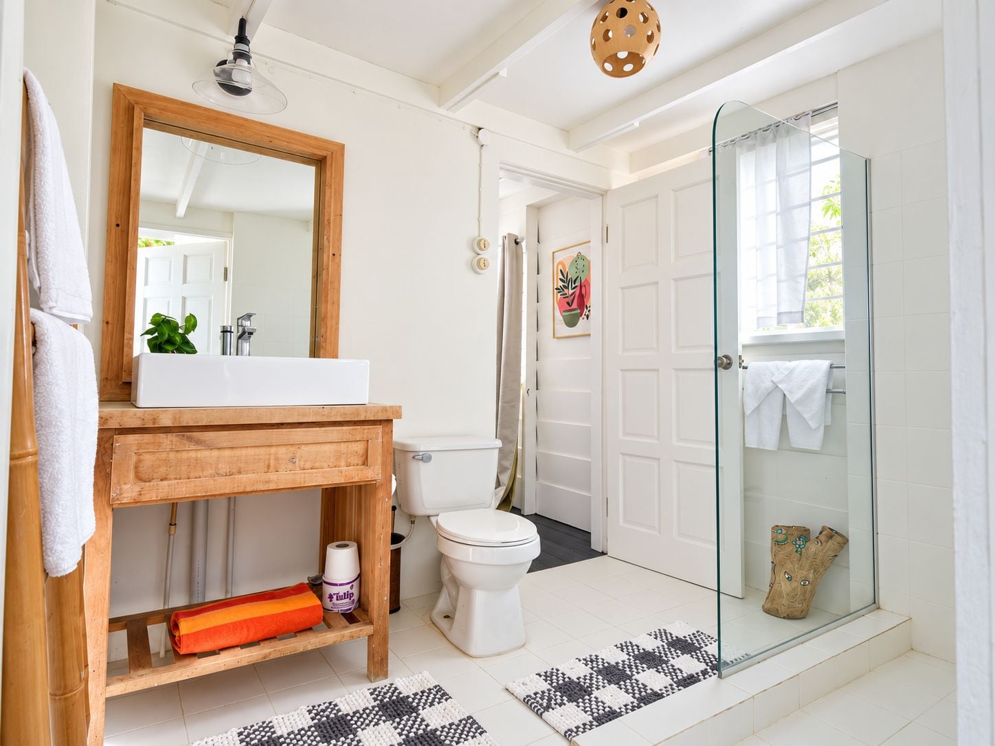 A modern bathroom with a wooden vanity, a white sink, a toilet, and a glass shower enclosure.