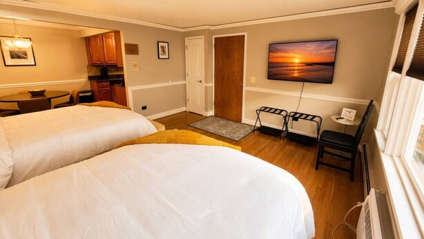 Habitació d'hotel amb dos llits, una taula, una cadira, un televisor i un quadre al mur.