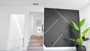En modern inredning med en trappa, en svart vägg med geometriskt mönster och en krukväxt.