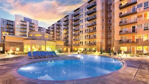 Un hotel con piscina, diversi balconi e un esterno luminoso.