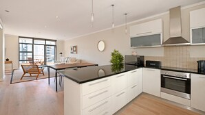 A modern kitchen with white cabinets, a black countertop, and stainless steel appliances. - Two Bed Apt | Foreshore | Pool | Gym | Secure (Cape Town)