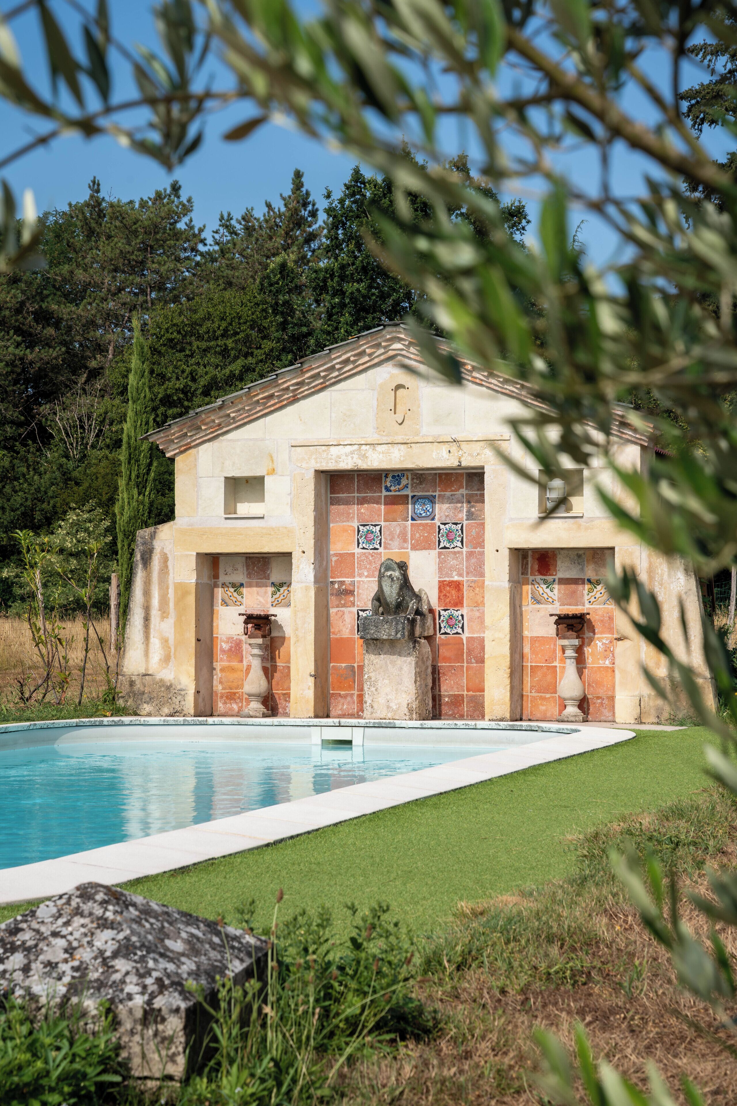 Un bâtiment à la façade recouverte de carreaux, avec une piscine et une statue devant.