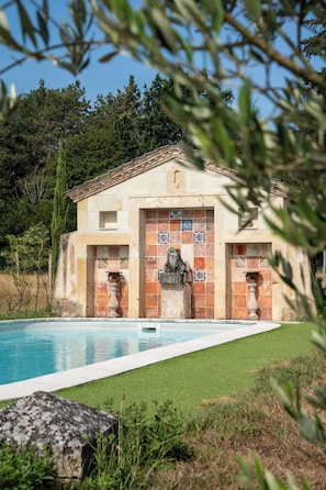 A building with a tiled facade, a pool, and a statue in front.