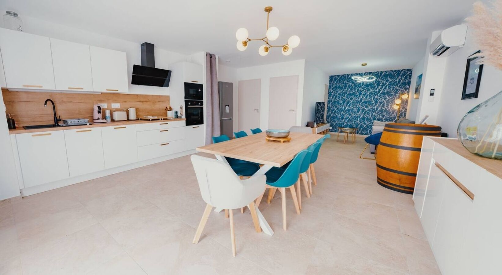Eine moderne Küche mit weißen Schränken, einer Holzausziehtafel und einem Essbereich mit einem Holztisch und Stühlen.
