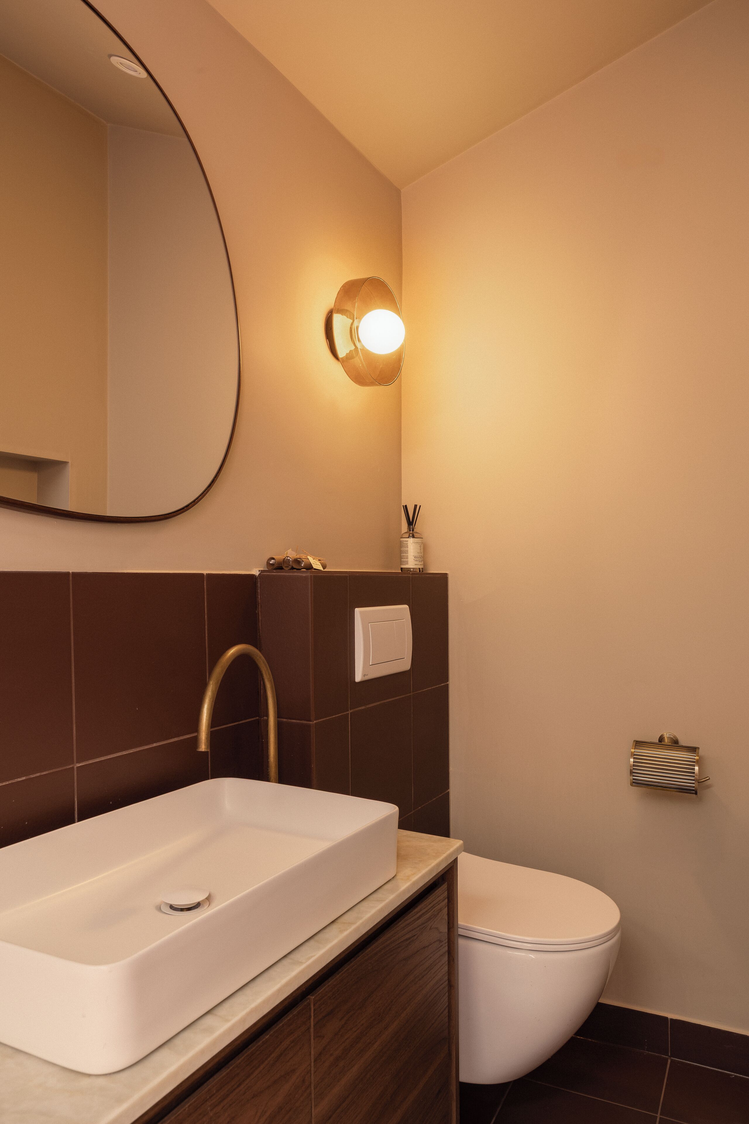 A modern bathroom with a rectangular sink, a toilet, a wall-mounted mirror, and a light fixture.