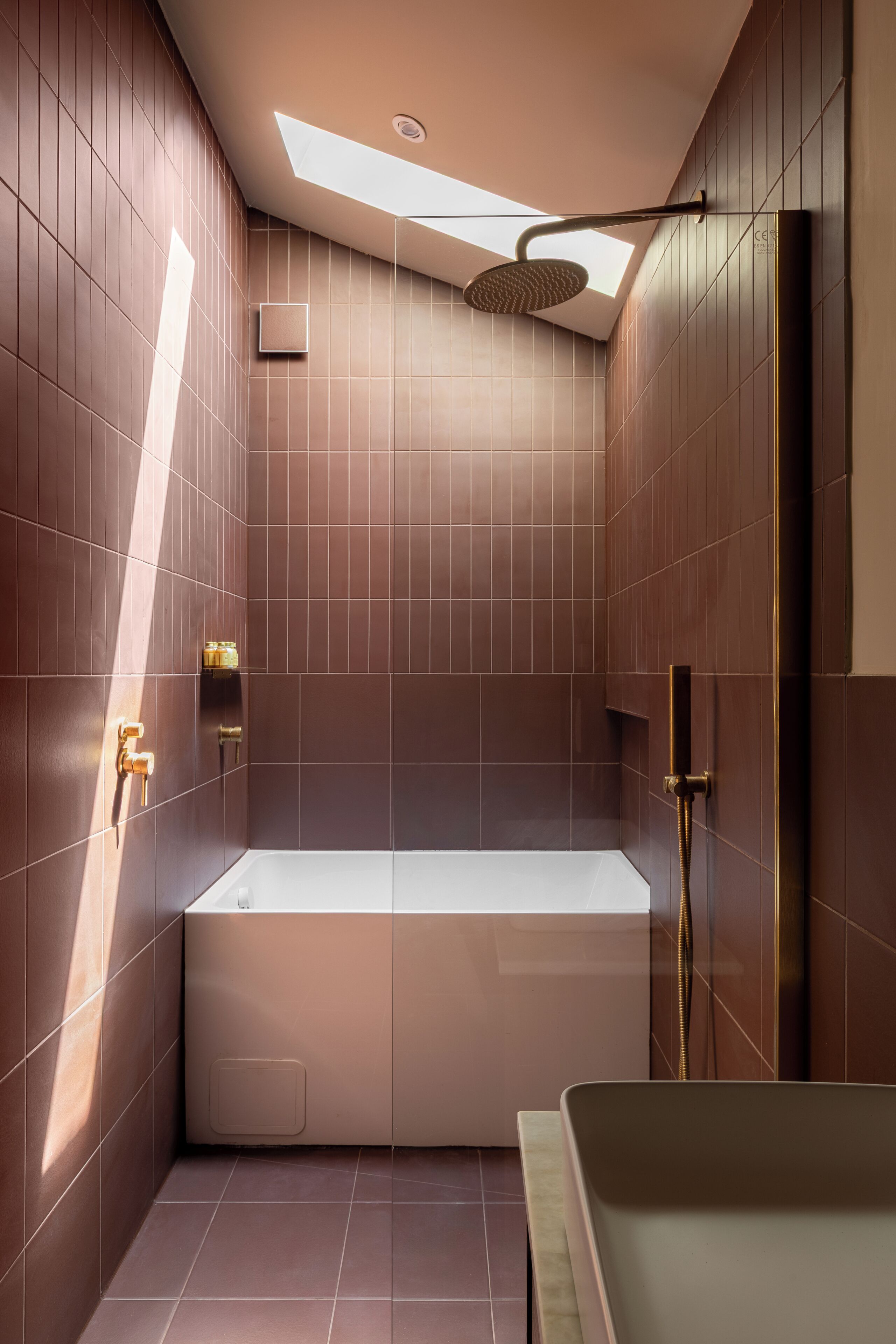 A modern bathroom with a bathtub, shower, and skylight.