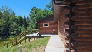 Eine Blockhütte mit einem Betonweg, der zu einer Holzterrasse führt.