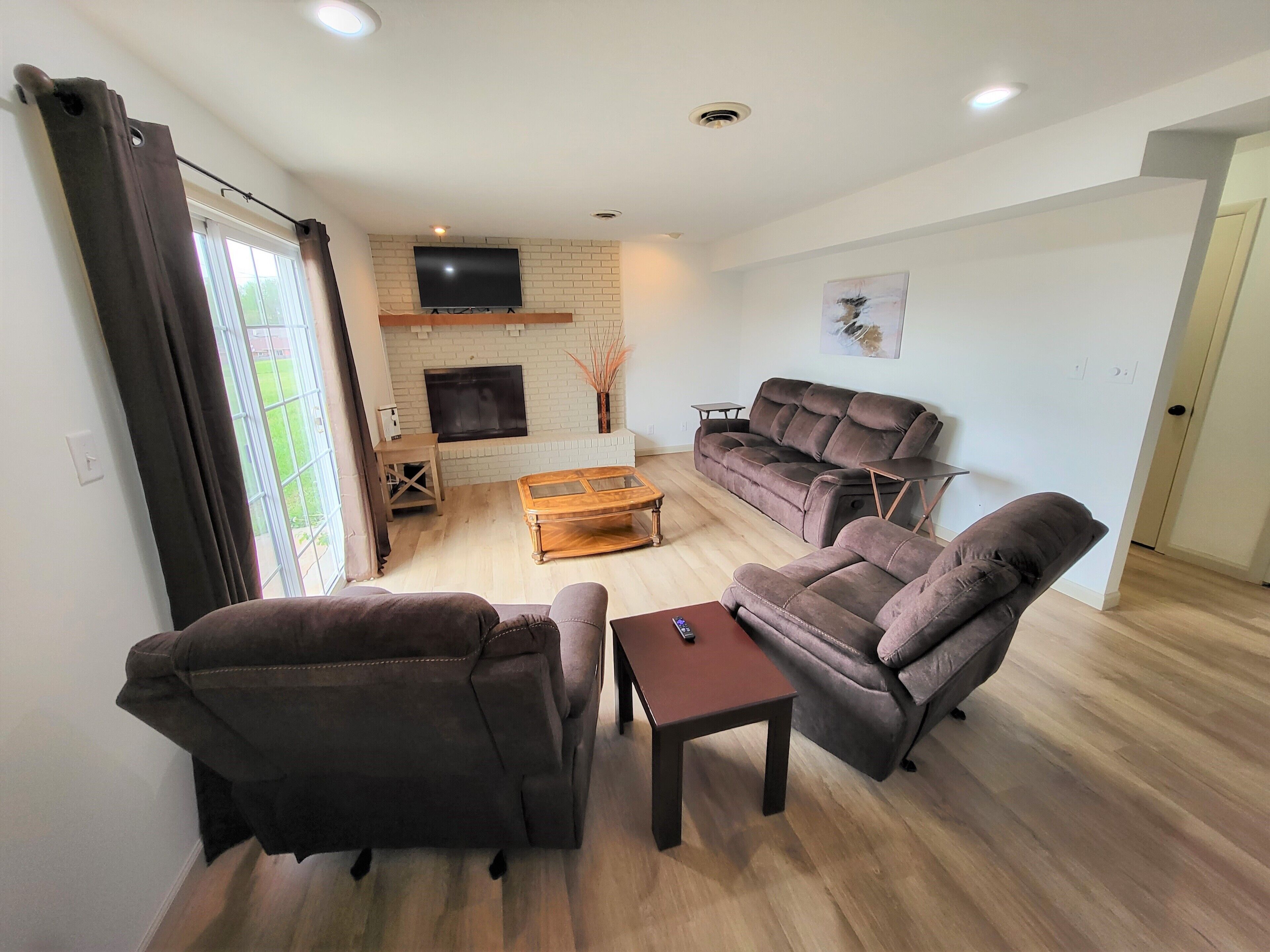 A living room with a sofa set, a coffee table, and a TV mounted on a brick wall.
