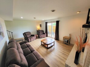 Una sala de estar con un sofá seccional, dos sillones, una mesa de centro y un ventanal corredizo que da a un patio.