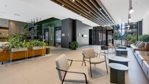 Eine moderne Lobby mit Sitzbereichen, einem Empfangstresen und einer Treppe.