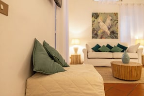 A living room with a sofa, pillows, a round wooden coffee table, and a painting on the wall. - Campo dei Fiori Silver Apartment (Roma)