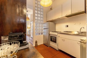A kitchen with a stove, oven, and sink, wooden cabinets, and a window with a decorative glass panel. - Campo dei Fiori Silver Apartment (Roma)