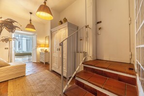 A staircase with red tiles leading to a landing, a white cabinet with decorative carvings, and a hanging lamp with a beige shade. - Campo dei Fiori Silver Apartment (Roma)