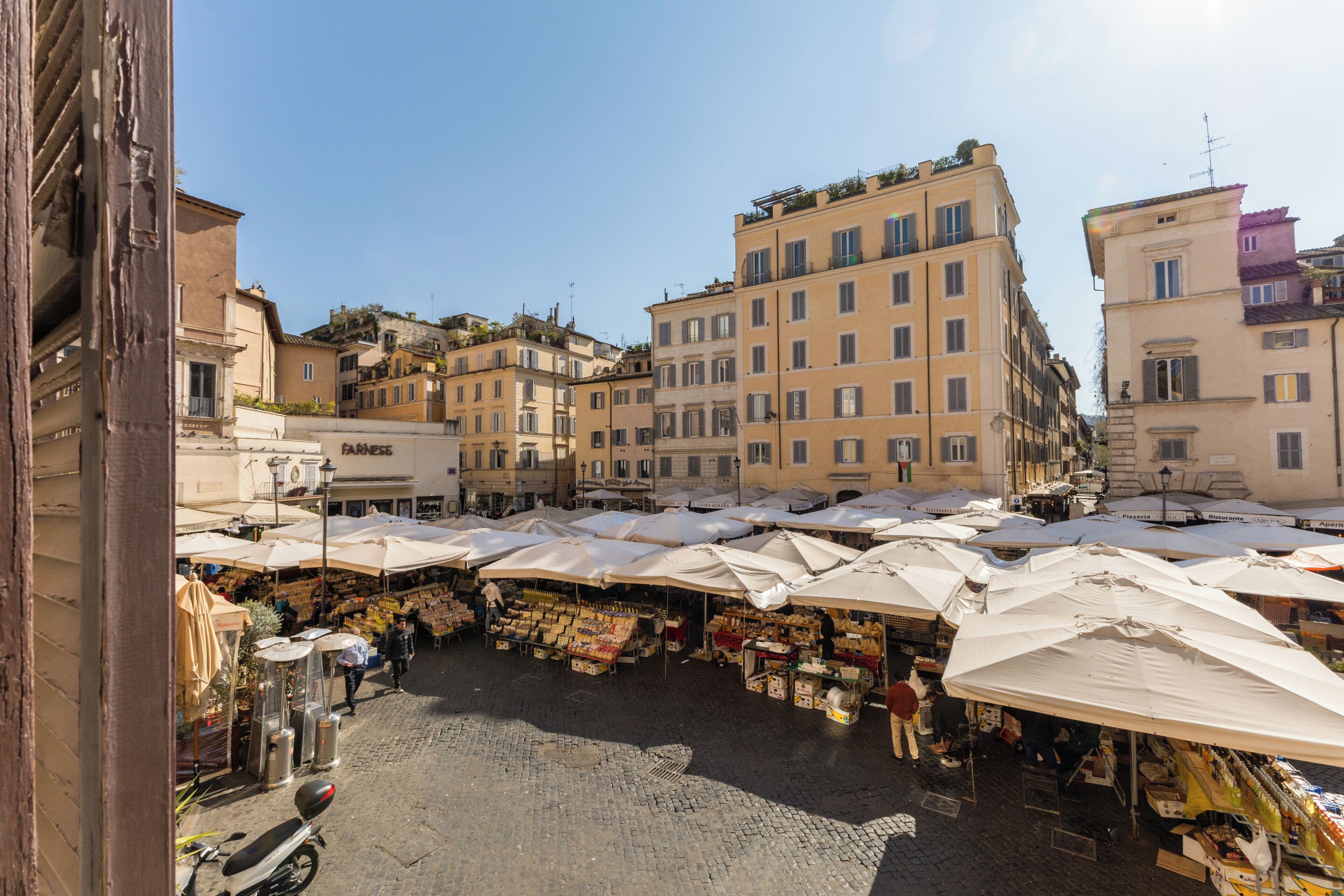 A bustling outdoor market with vendors and stalls, surrounded by historic buildings.