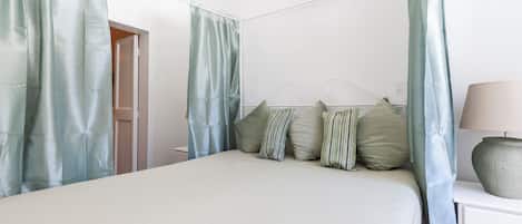 A bedroom with a bed, curtains, a bedside table, and a lamp.