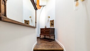En trappe med trætrin, en mørk trækommode og et spejl monteret på væggen.