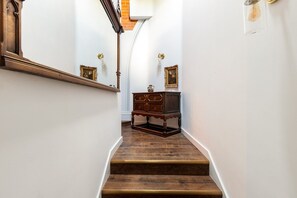 Eine Treppe mit Holzstufen, eine dunkle Holzkommode und ein an der Wand befestigter Spiegel.