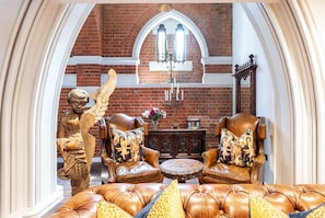 Ein Zimmer mit Backsteinwand, einer Statue, Ledermöbeln und einer Kristallleuchter.