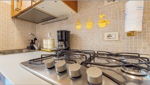Eine Küche mit Gasherd, Kaffeemaschine und gefliestem Fliesenspiegel.