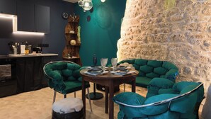 A modern interior with a stone wall, teal upholstered chairs, a wooden table, and a bar area. - Les Grèves, Village Center, 80 meters from the beach (Saint-Jacut-de-la-Mer)
