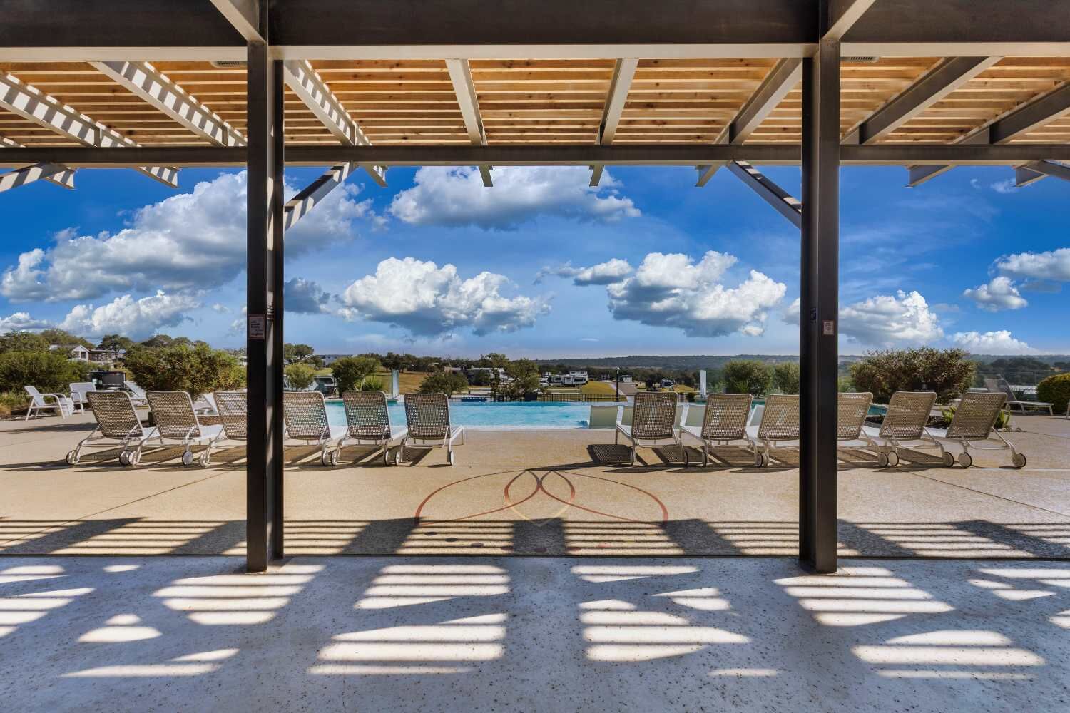 Un espacio al aire libre techado con sillones de descanso y una piscina.