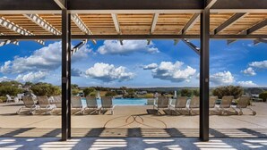 A covered outdoor area with lounge chairs and a swimming pool. - Tiny Home 140 - Evans Ranch (Fredericksburg)