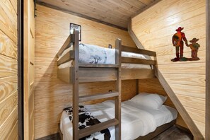 A bunk bed room with wooden walls and a welcome sign. - Tiny Home 140 - Evans Ranch (Fredericksburg)