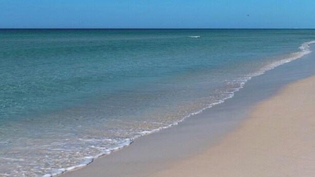 Una spiaggia con acque cristalline e una battigia sabbiosa.