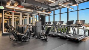 A gym with various exercise equipment, including treadmills and weight machines, and large windows offering a view of the city. - E2611 - West-View Studio with Balcony in Downtown Miami (Miami)