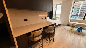 Uma cozinha moderna com balcão, dois bancos altos e uma grande janela com vista para a cidade.