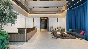 A modern hotel lobby with a reception desk, seating area, and a staircase leading to an upper floor. - E2611 - West-View Studio with Balcony in Downtown Miami (Miami)