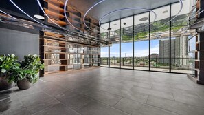 A spacious interior with a high ceiling, large windows offering a city view, and a modern shelving unit. - E2611 - West-View Studio with Pool and Gym in Downtown Miami (Miami)
