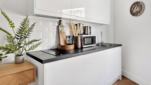 A modern kitchen with white cabinets, a black countertop, a microwave, and a sink. - Cozy and Lovely Studio - Close to everything! (London)
