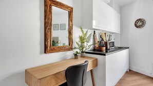 A modern kitchen with a wooden desk, a chair, a mirror, and a clock on the wall. - Cozy and Lovely Studio - Close to everything! (London)