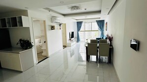 A spacious living area with a dining table and chairs, a sofa, and a TV. - Diamond Luxury (Ho Chi Minh City)