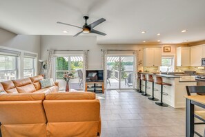 A modern living room with a sofa, a TV, and a dining area with bar stools. - Boathouse, Dock & Sunset Views! Muskrat Lake Home (Gobles)
