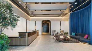 A modern lobby with a reception desk, seating area, and a staircase leading to an upper level. - E4103A - Studio with North Views and Pool in Downtown Miami (Miami)