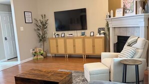 En stue med sofa, sofabord, fjernsyn, pejs og en loftventilator.