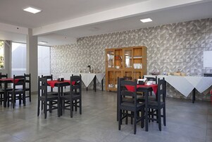 Un comedor con mesas y sillas, un aparador de madera y una pared con textura.