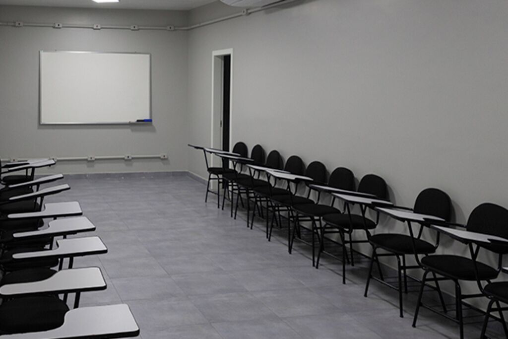 Una sala de conferencias con una pizarra, filas de mesas y sillas, y una puerta.