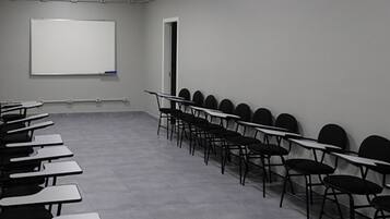 Una sala de conferencias con una pizarra, filas de mesas y sillas, y una puerta.