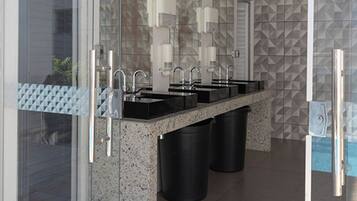 A modern bathroom with multiple sinks, a glass partition, and a geometric tile backsplash.