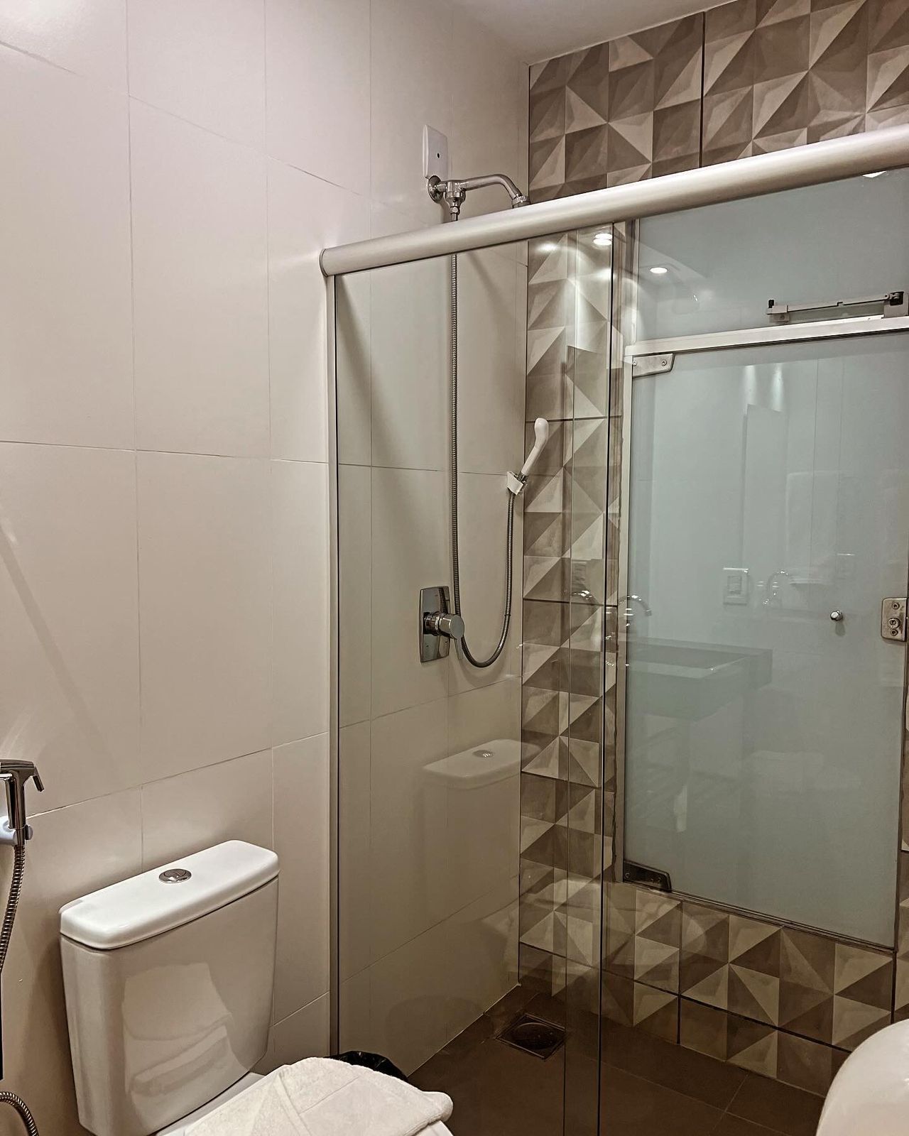 Un baño moderno con cabina de ducha de vidrio, inodoro y lavamanos.