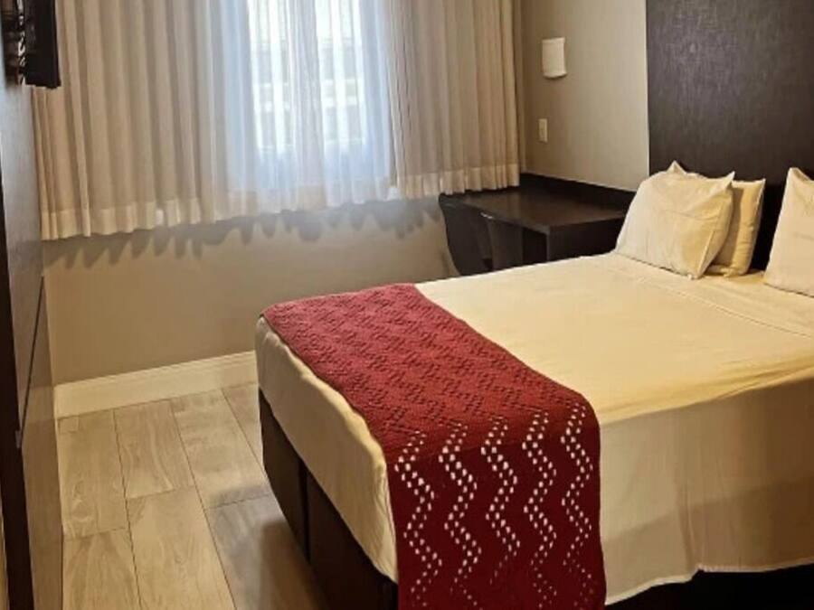 A hotel room with a bed, a desk, and a chair.