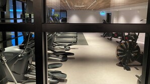 Et fitnessrum med træningsudstyr, løbebånd og spinningcykel.