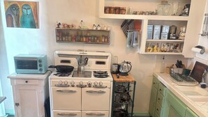 A vintage kitchen with a checkered floor, a white stove, a toaster, and shelves with kitchenware. - Beautiful Spanish Style house in Silver Lake With Garden (Los Angeles)