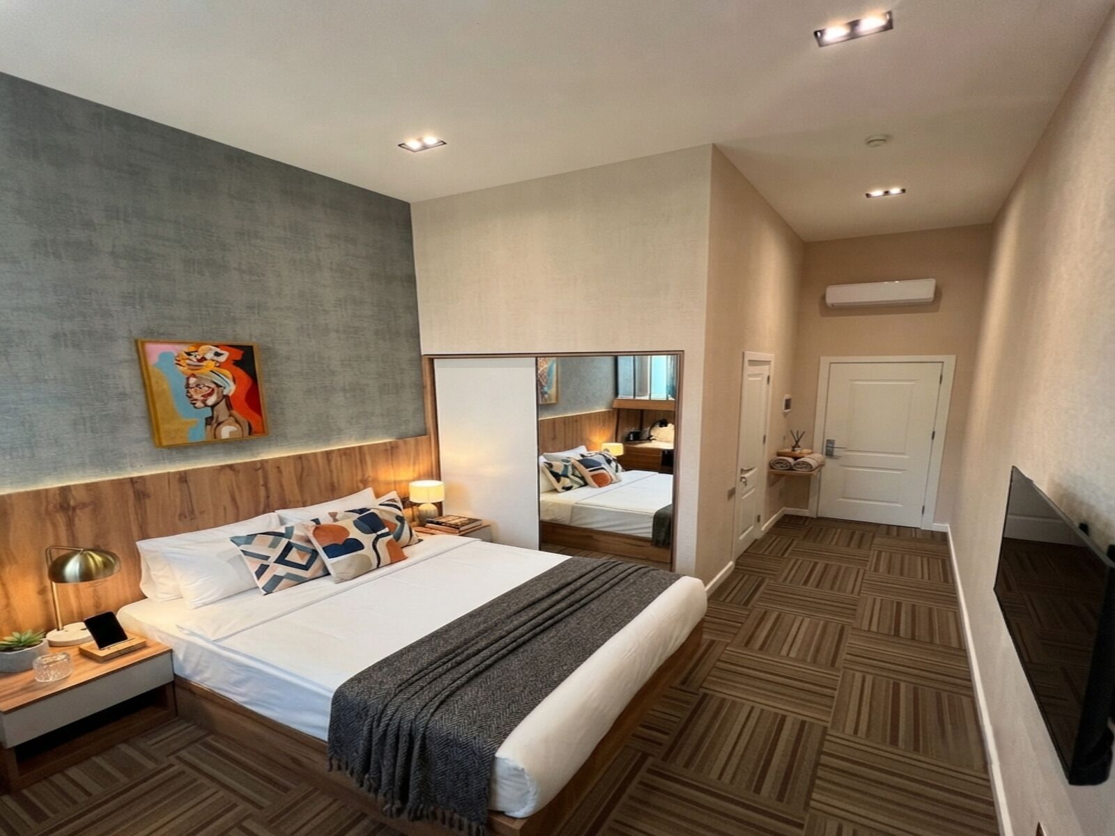 Une chambre d’hôtel moderne avec un grand lit, des tables de chevet, un miroir et un téléviseur.