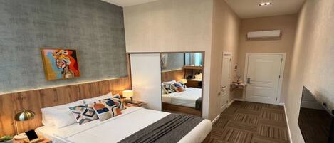 Une chambre d’hôtel moderne avec un grand lit, des tables de chevet, un miroir et un téléviseur.