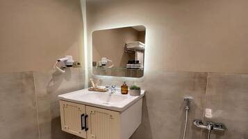 A bathroom with a white sink, a mirror, a towel rack, and a shower.