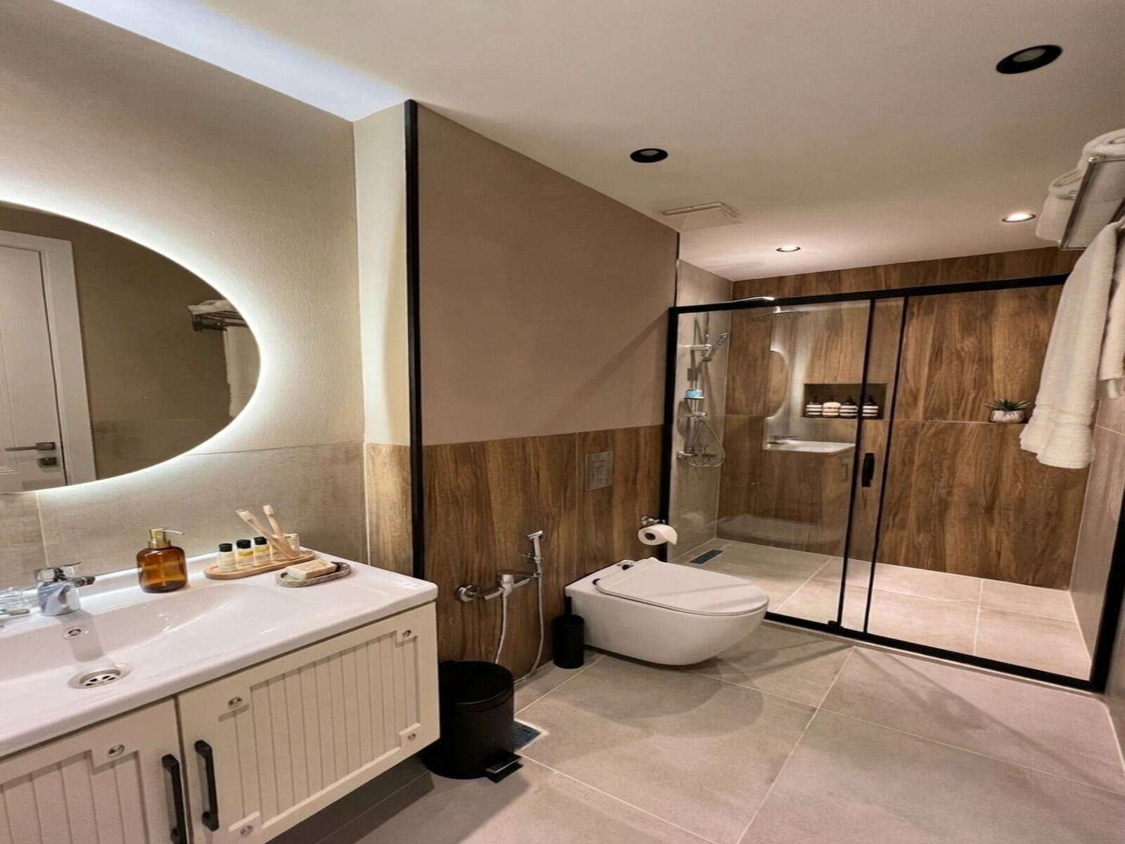 Une salle de bain moderne avec un grand miroir, une douche et des toilettes.